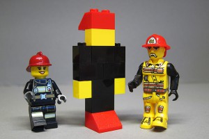 Några historiska LEGO-brandmän. Äldst i mitten  set nr 305, Fire Engine, från 1964 (reproduktion), till höger 4 Juniors set nr 4601, Fire Cruiser, från 2001 och till vänster City set nr 60003, Fire Emergency, från 2013.